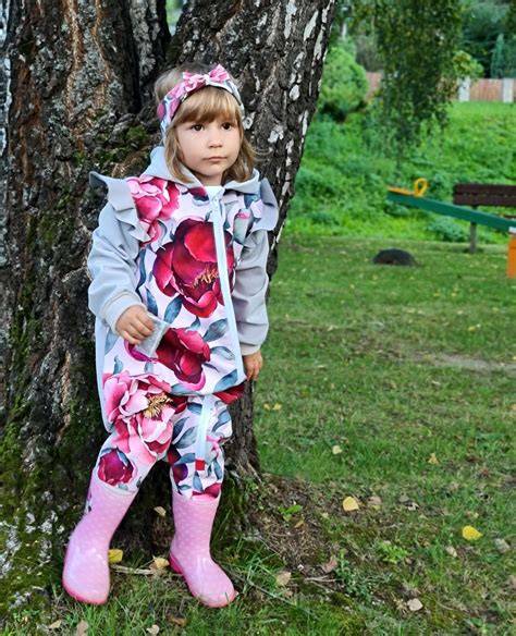 Obrázok detí hrajúcich sa vonku v škôlke s typickou výbavou (nepremokavý overal, gumáky, teplé oblečenie).