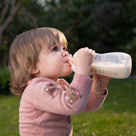Ilustrácia bábätka pijúceho z dojčenskej fľaše Natural