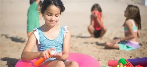 Deti na pláži s klobúkmi a opaľovacím krémom