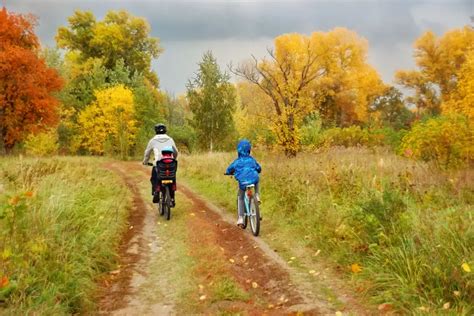 Ilustrácia rodiny jazdiacej na bicykloch s dieťaťom vo cyklovozíku